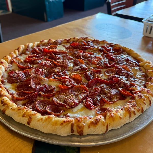 A freshly baked pepperoni pizza with a thick, golden crust sits on a metal pan.