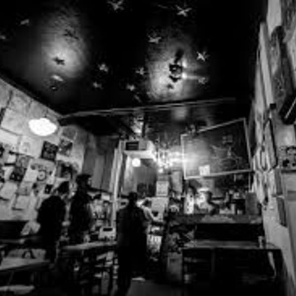 Black and white photo of a dimly lit, eclectic restaurant interior with people and star-shaped lights.
