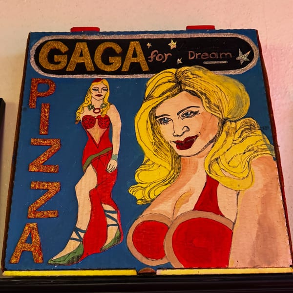 Hand-painted sign for "Gaga for Dream Pizza" featuring two blonde women in red dresses.