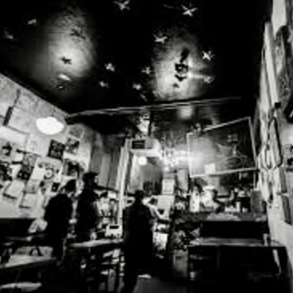 Black and white photo of a dimly lit, eclectic restaurant interior with patrons and star-shaped ceiling lights.